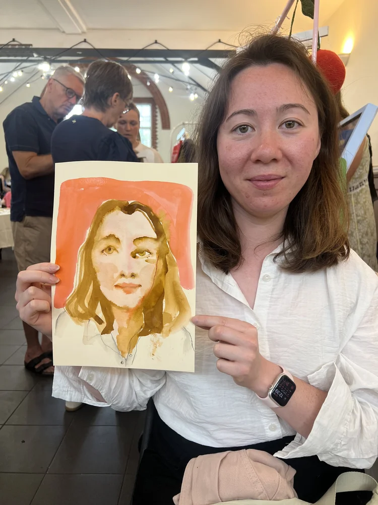 A guest holds the hand-drawn watercolour portrait Tracey Smith has just created of her at a live event in London.