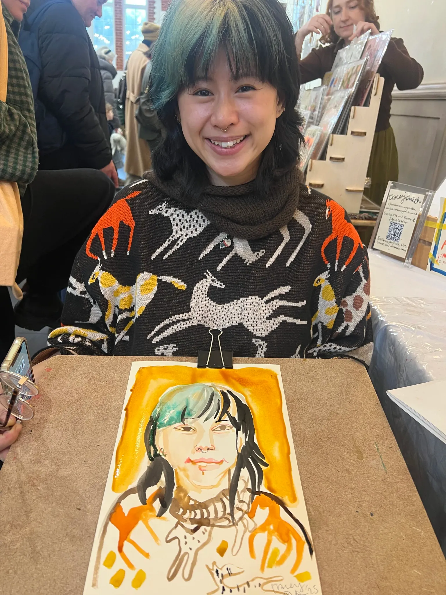 People holding watercolour portraits at event.