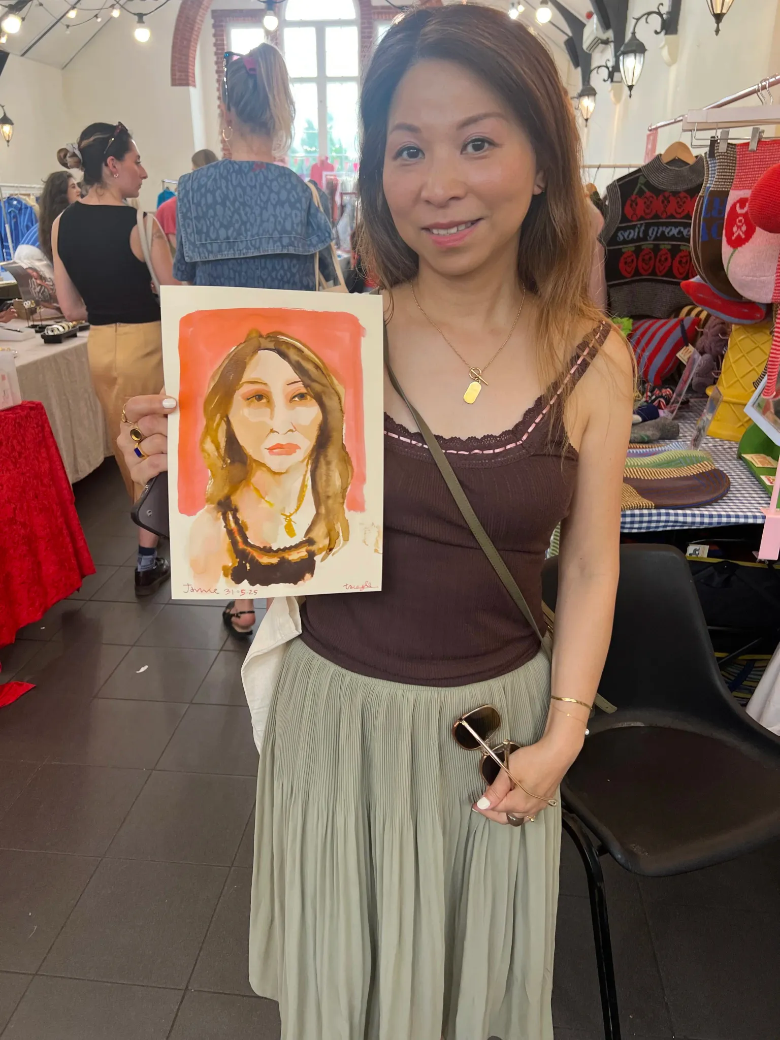 Smiling woman in brown top holding portrait.