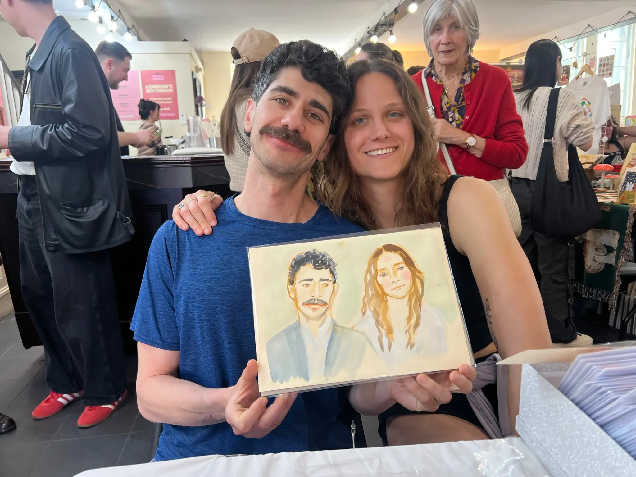 Smiling couple holding their watercolour portrait.