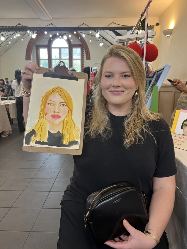 Smiling woman holding her watercolour portrait.
