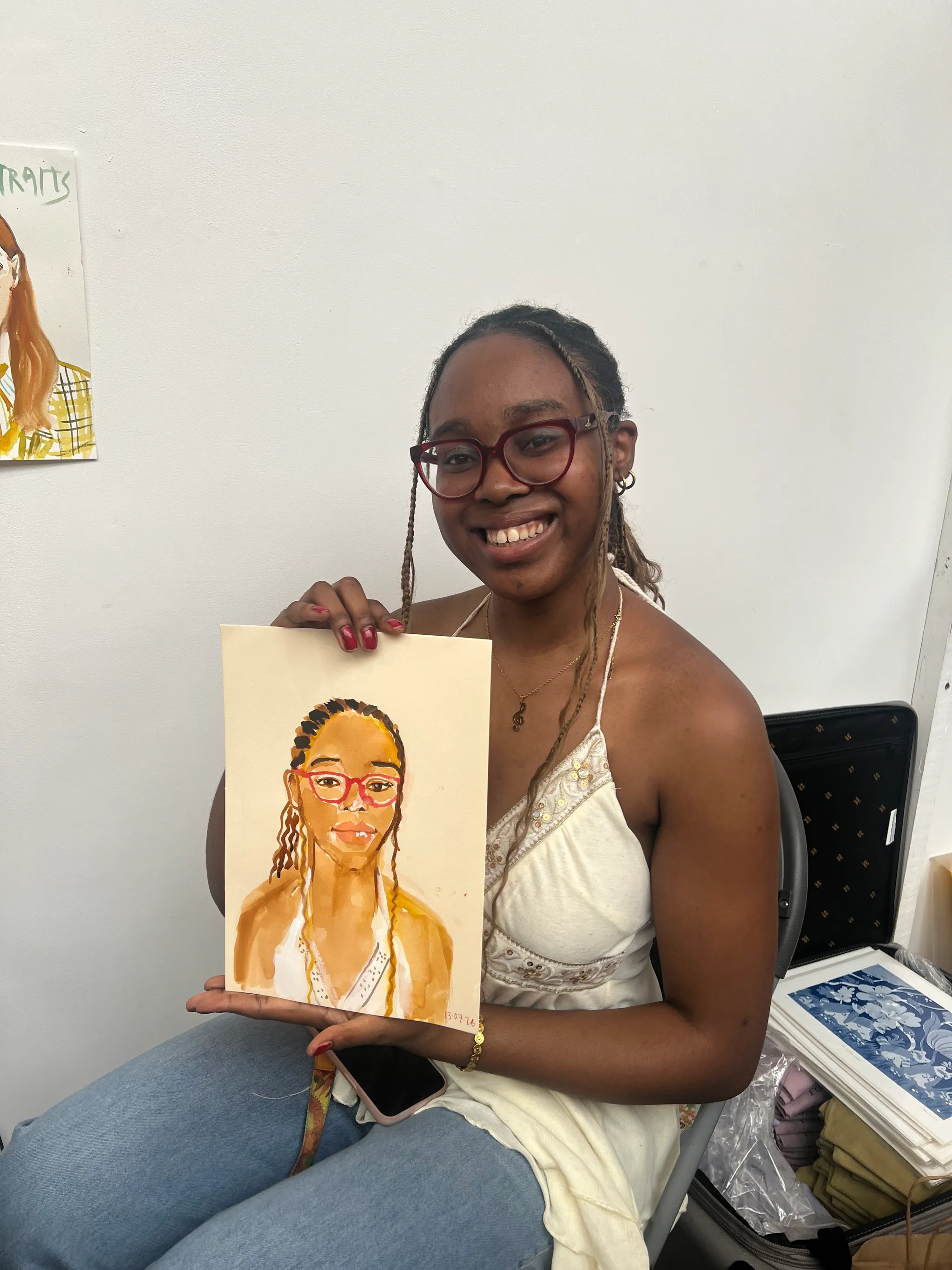 People holding watercolour portraits at event.