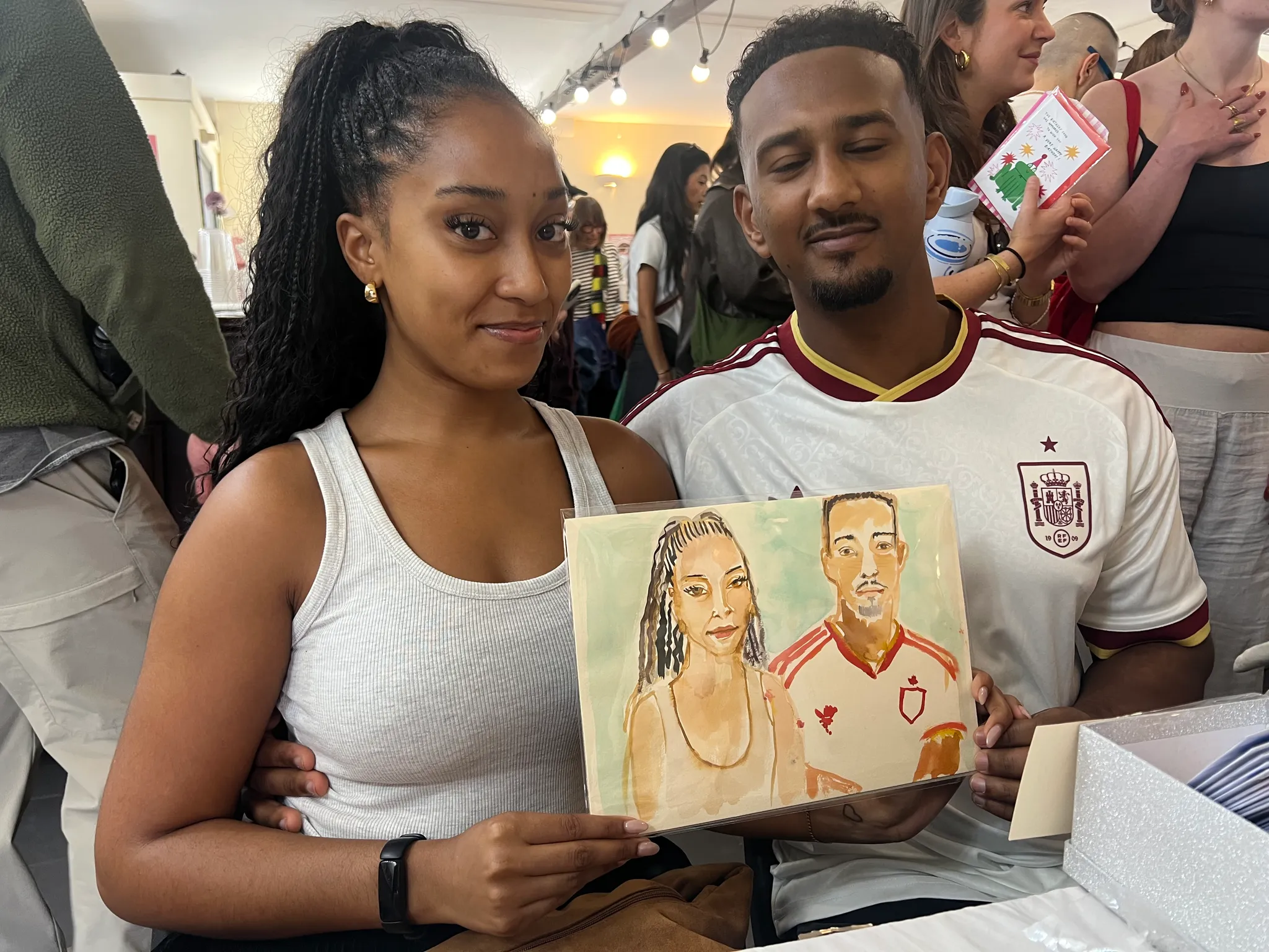 People holding watercolour portraits at event.